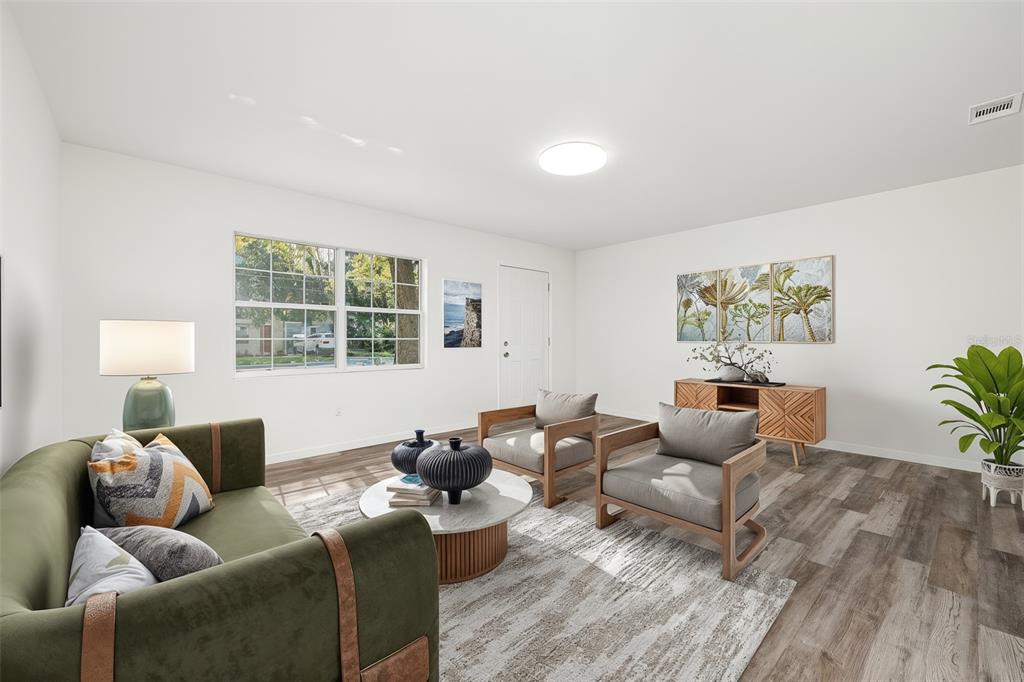 A living room features a green sofa, two armchairs, a coffee table, and wood-look flooring — 2100 SE 50TH STREET, GAINESVILLE, FL