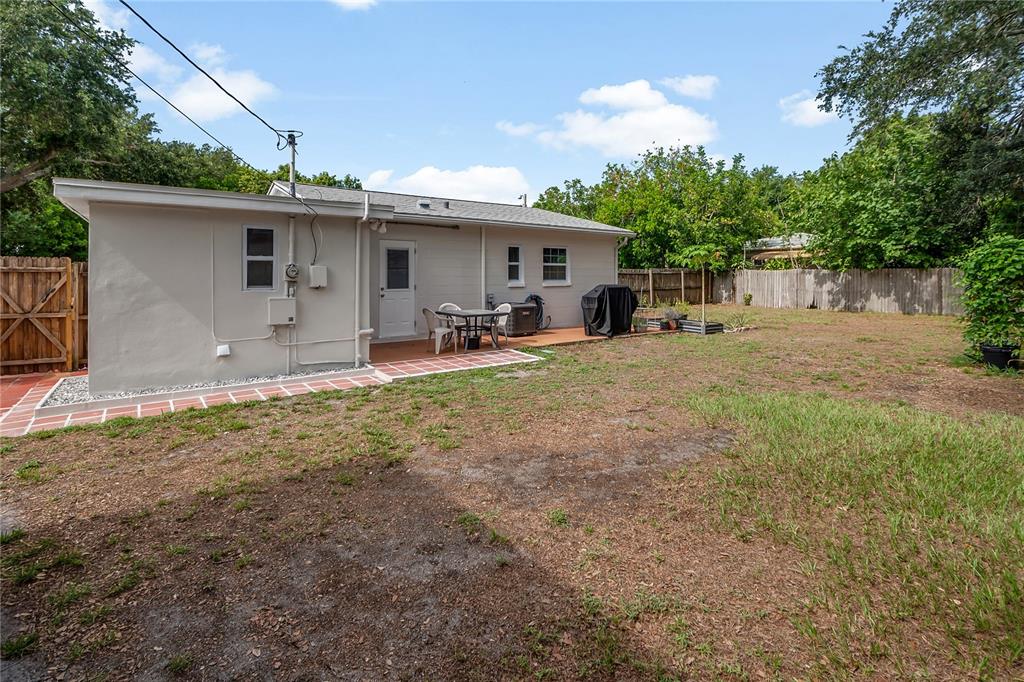 The exterior of a single-story house features a small patio, a fenced yard, and trees — 2151 44TH AVENUE N, ST PETERSBURG, FL