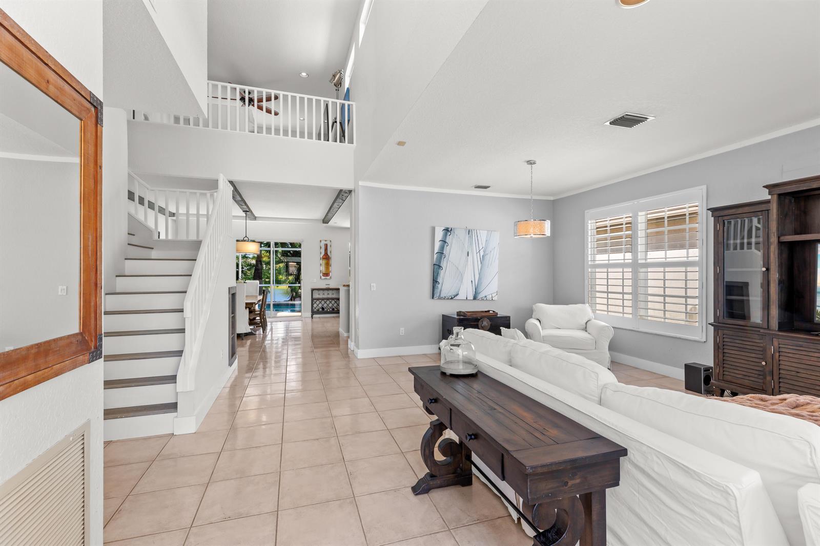 A living room with tile floors, a white sofa, and a staircase leading to a loft — 7611 Doubleton Drive, Delray Beach FL 33446, DELRAY BEACH, FL