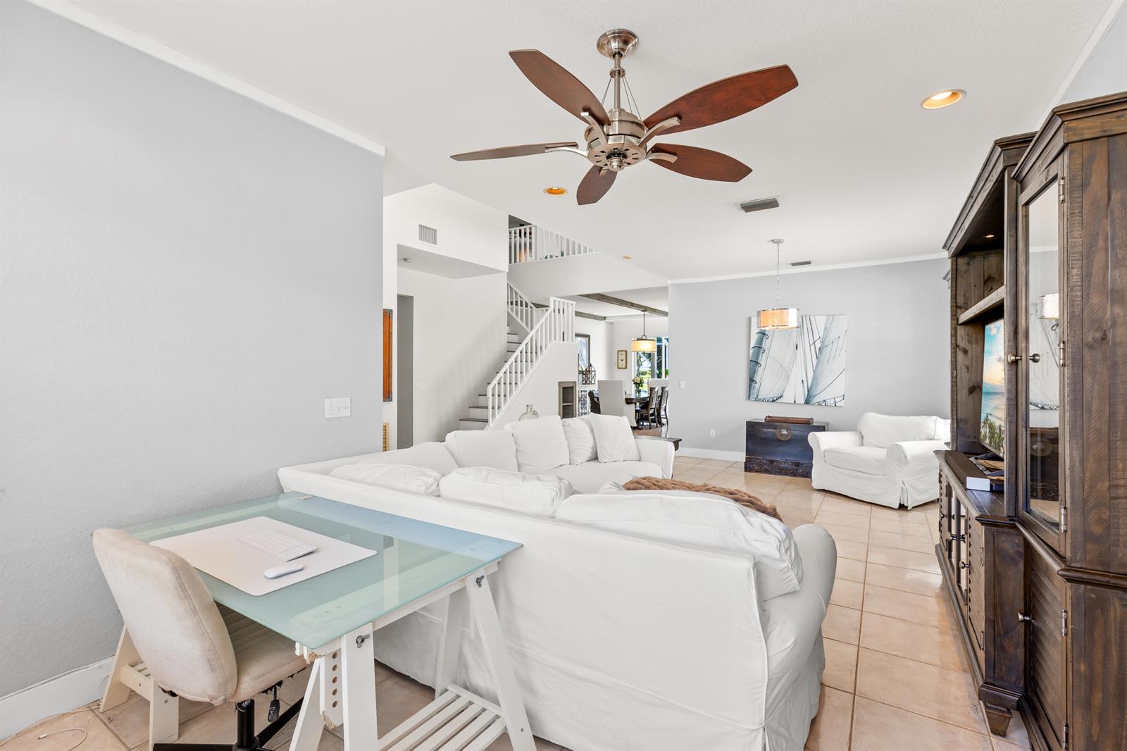 A living room features a white sectional sofa, a glass-topped desk, and a wooden entertainment center — 7611 Doubleton Drive, Delray Beach FL 33446, DELRAY BEACH, FL
