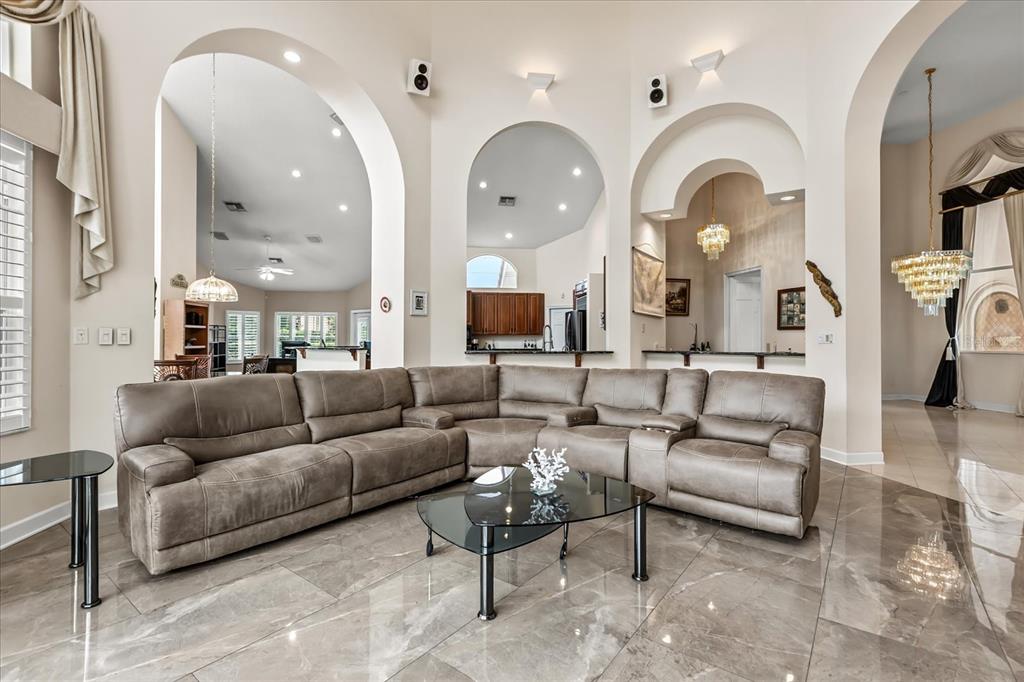 A living room features a large gray sectional sofa, a glass coffee table, and arched openings — 1036 GOLF VALLEY DRIVE, APOPKA, FL