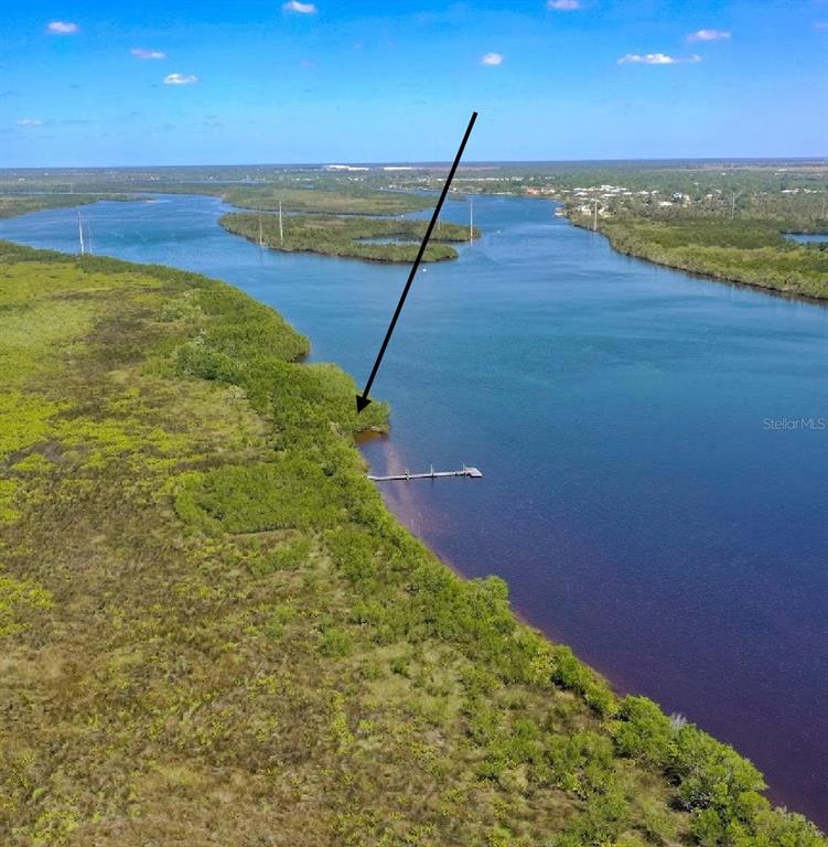An aerial view shows a wooden dock extending into a river from a vegetated shoreline — 2312 SORRENTO COURT, PUNTA GORDA, FL