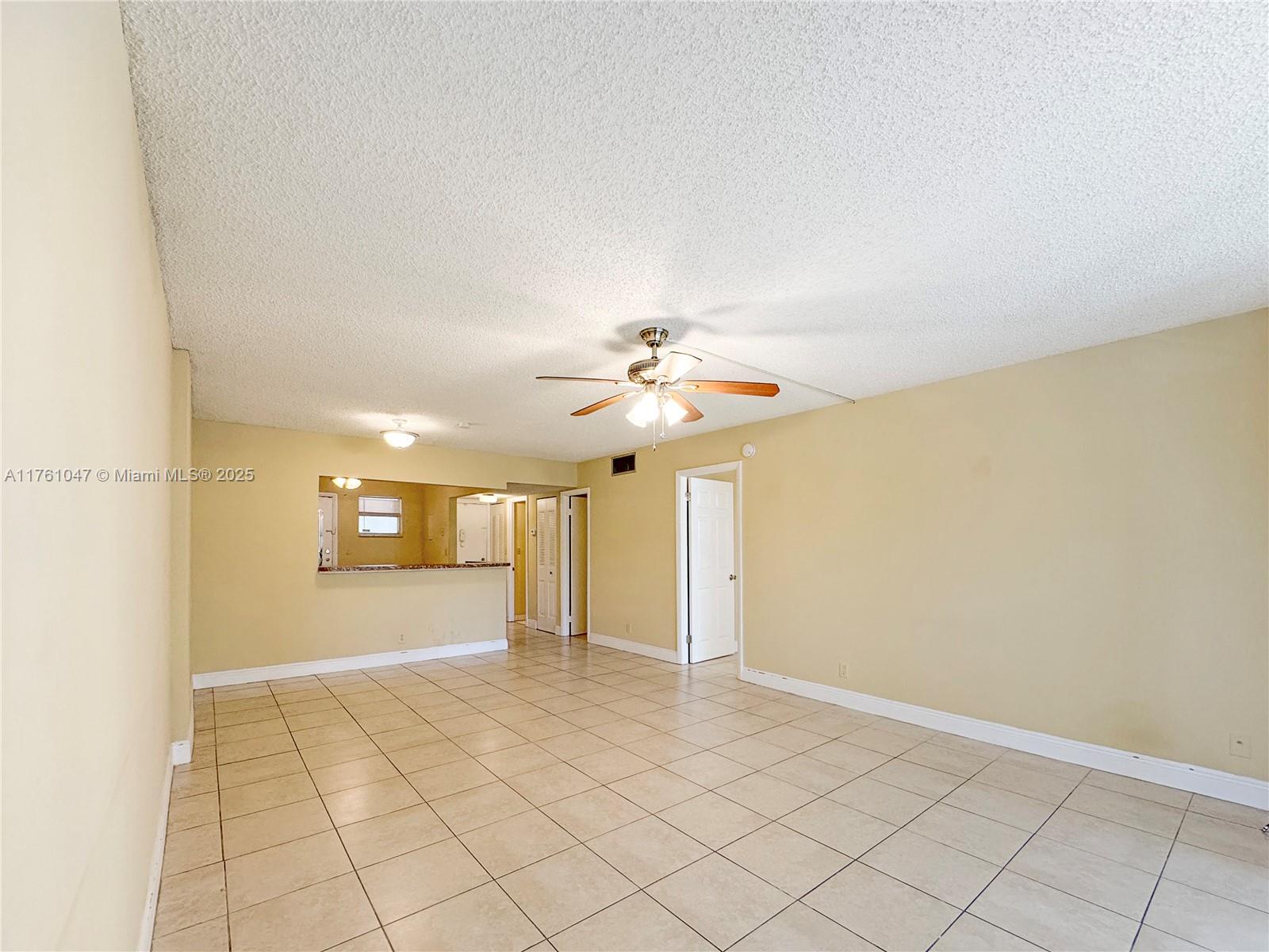 An empty room with beige tile floors, a popcorn ceiling, and a ceiling fan — 410 NW 68th Ave # 207, Plantation FL 33317, PLANTATION, FL