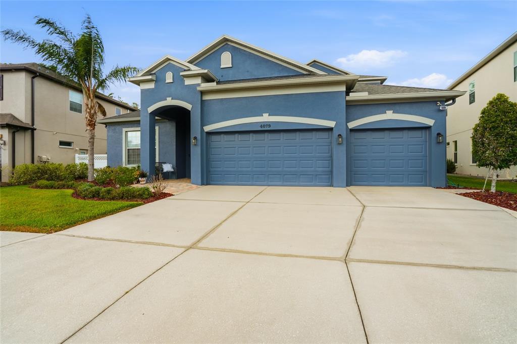 A covered patio features a dining set, a swimming pool, and a white picket fence — 4079 WINDCREST DRIVE, WESLEY CHAPEL, FL