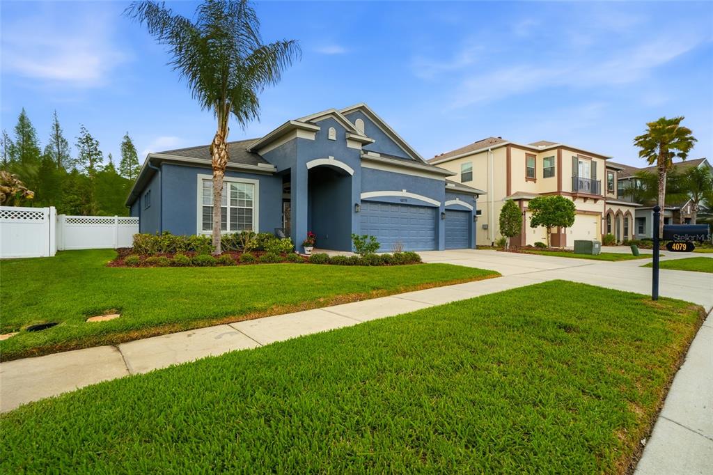 A living room features a tray ceiling, tile flooring, a large sectional, and sliding glass doors — 4079 WINDCREST DRIVE, WESLEY CHAPEL, FL