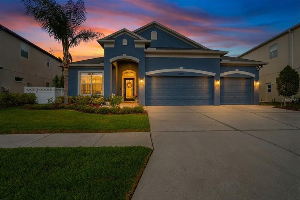A bedroom features a tray ceiling, wood-look flooring, a bed, an armchair, and a television — 4079 WINDCREST DRIVE, WESLEY CHAPEL, FL