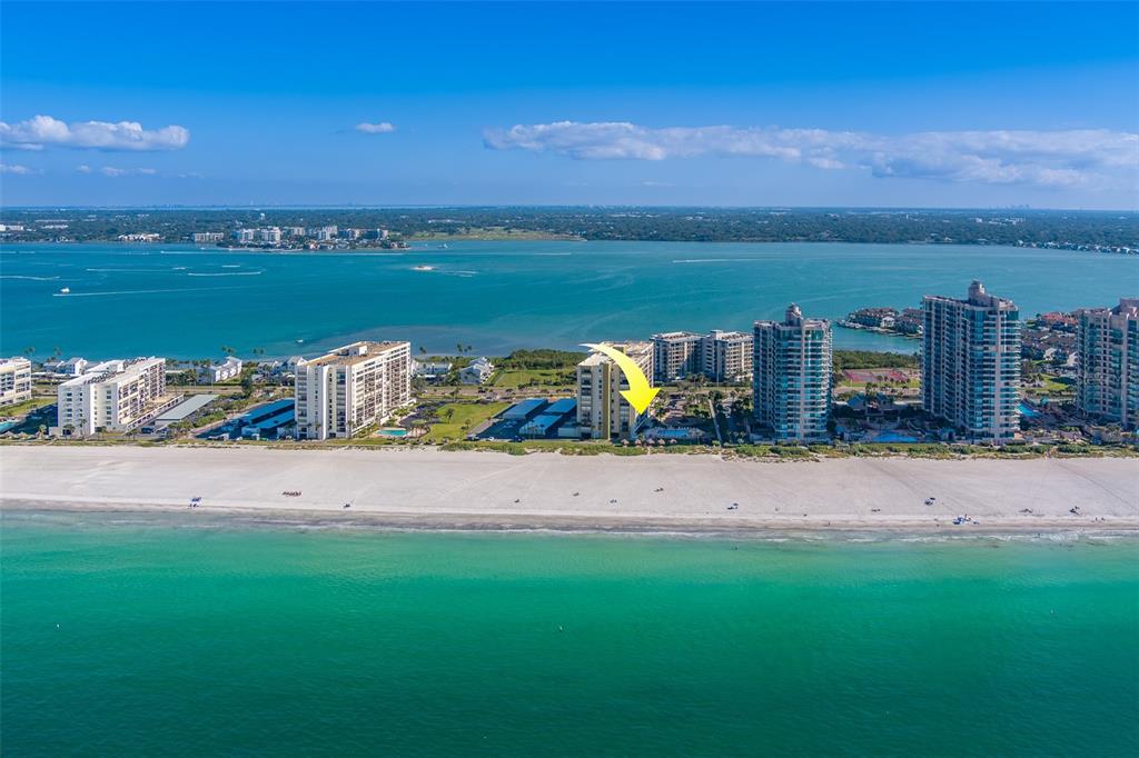 An aerial view of a beachfront high-rise building marked with a yellow arrow — 1480 GULF BOULEVARD UNIT 201, CLEARWATER BEACH, FL