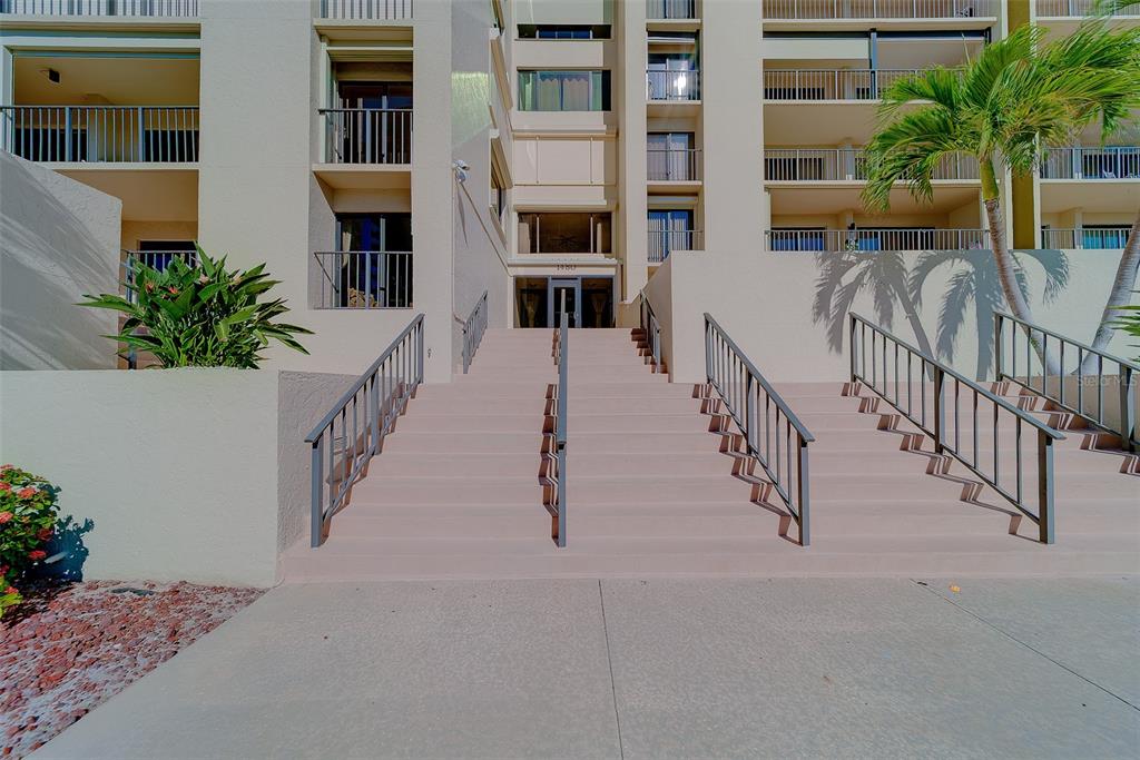 A wide set of concrete stairs leads to the entrance of a multi-story apartment building — 1480 GULF BOULEVARD UNIT 201, CLEARWATER BEACH, FL