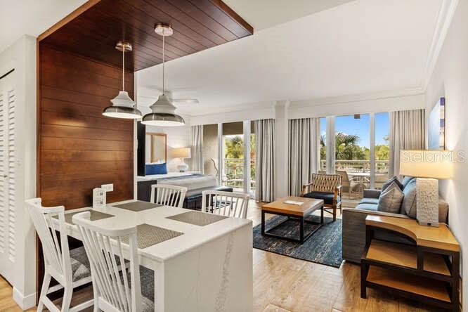 A dining area with pendant lights leads into a living room with a balcony view — 250 SANDS POINT ROAD UNIT 5203, LONGBOAT KEY, FL