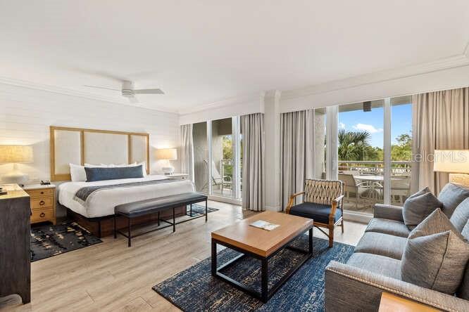A bedroom with a king bed, seating area, and sliding glass doors leading to a balcony — 250 SANDS POINT ROAD UNIT 5203, LONGBOAT KEY, FL