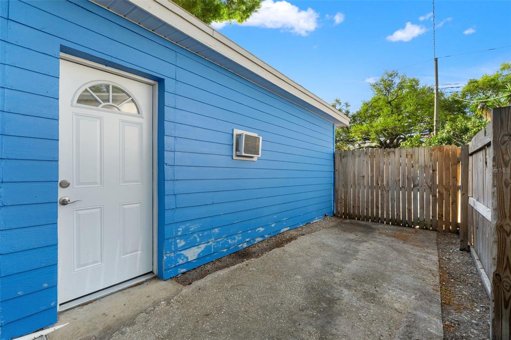 A blue exterior wall with a white door and a small window next to a fence — 8996 SOUTHERN COMFORT DRIVE, LARGO, FL