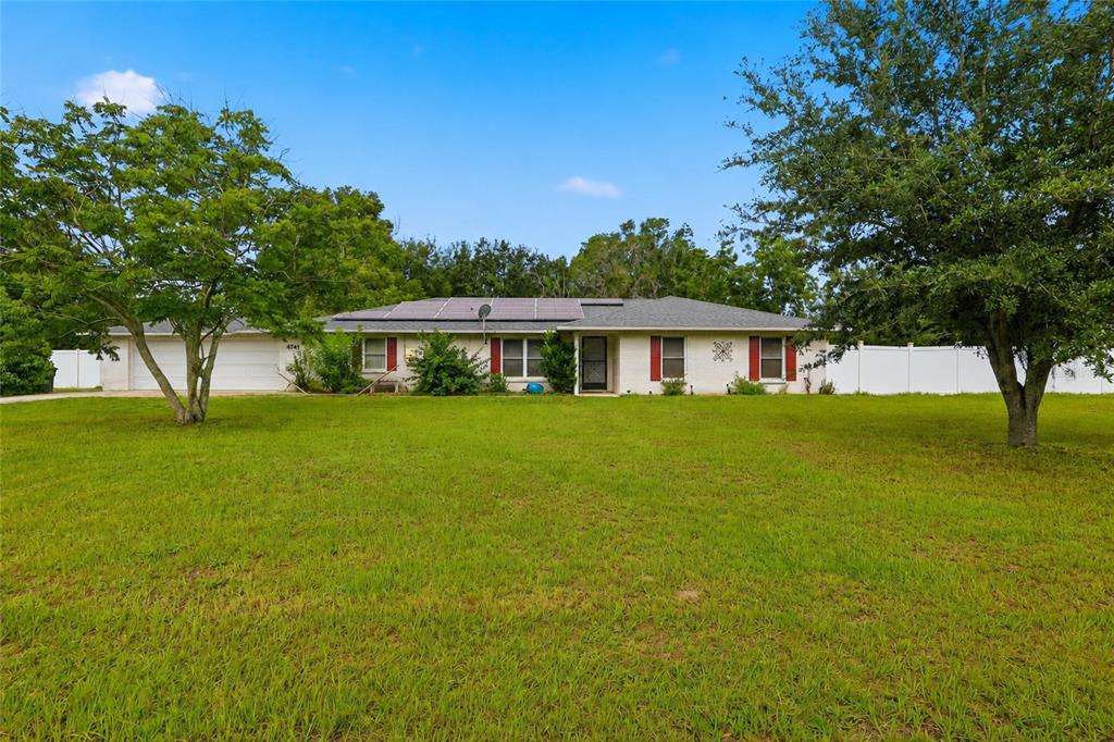 A single-story brick house with a solar panel roof and a large front lawn — 4741 SEABERG ROAD, ZEPHYRHILLS, FL