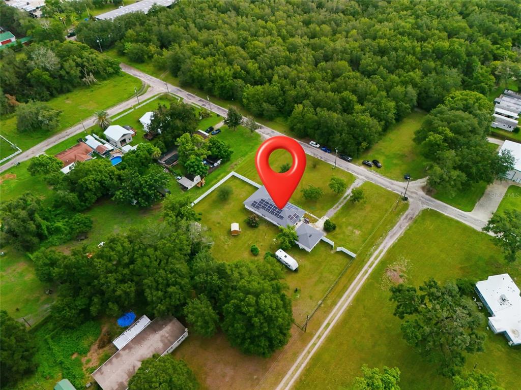 An aerial view shows a house with solar panels on a large, grassy, wooded lot — 4741 SEABERG ROAD, ZEPHYRHILLS, FL