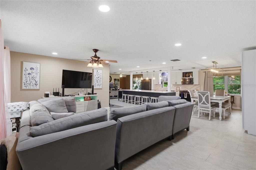 An open-concept living room and kitchen featuring a large gray sectional sofa and dining area — 4741 SEABERG ROAD, ZEPHYRHILLS, FL