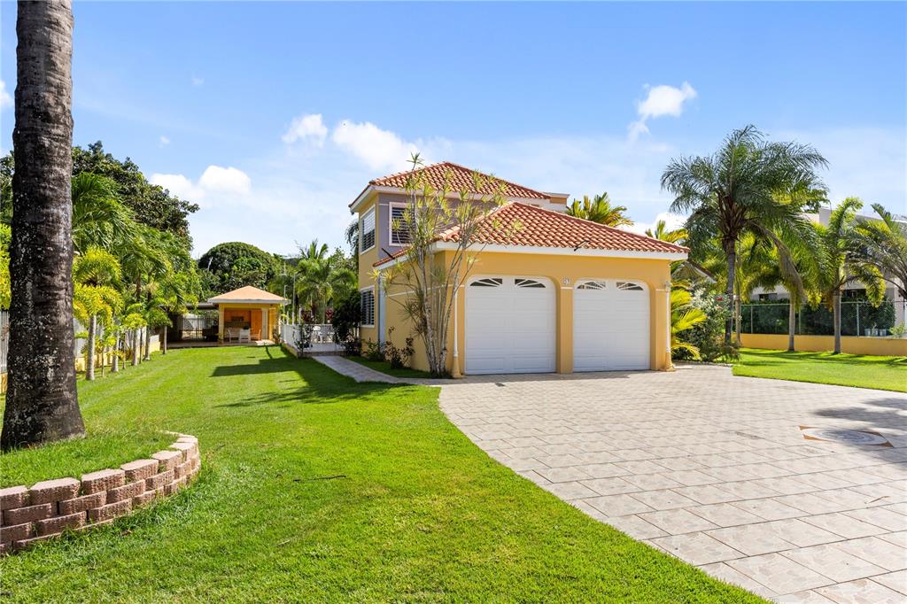 A two-story yellow house with a two-car garage and a detached gazebo in the yard — HACIENDA LAS PALMA TIERRAS NUEVAS, MANATI, PR
