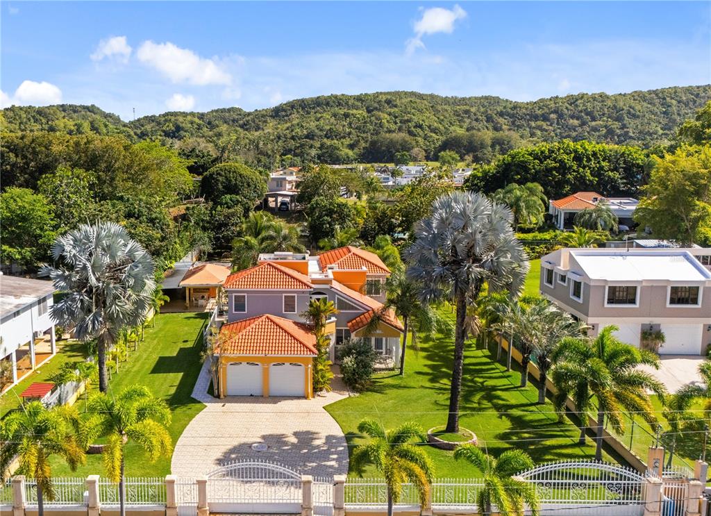 An aerial view shows a two-story house with a terracotta roof and a paved driveway — HACIENDA LAS PALMA TIERRAS NUEVAS, MANATI, PR