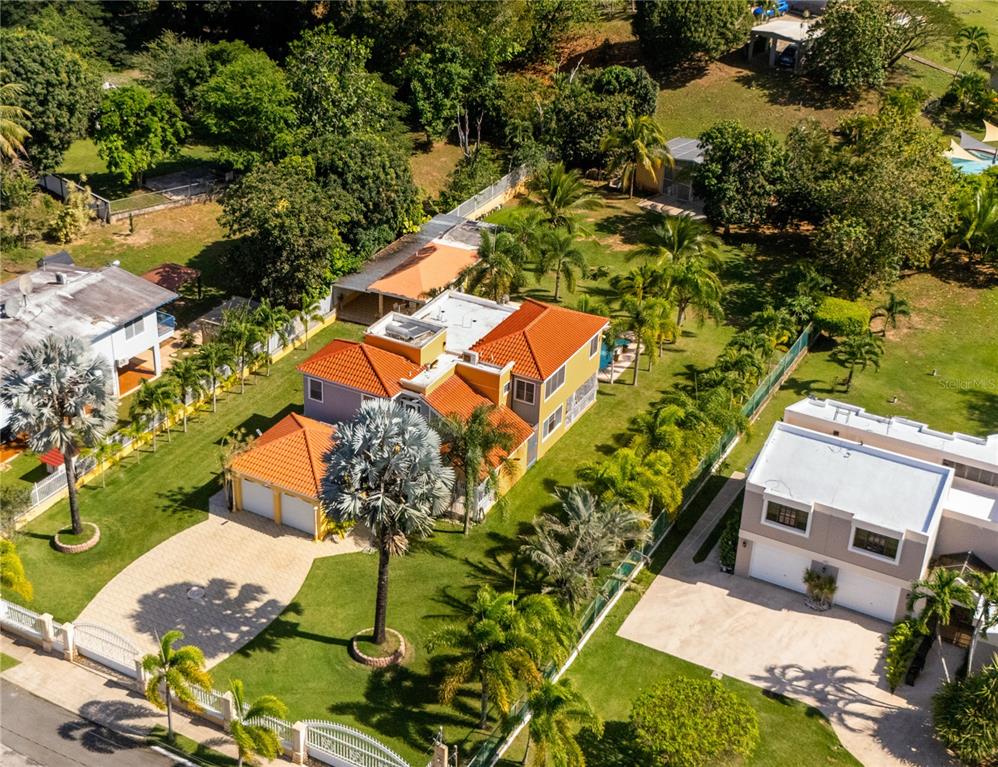 An aerial view shows a two-story house with a red tile roof and palm trees — HACIENDA LAS PALMA TIERRAS NUEVAS, MANATI, PR