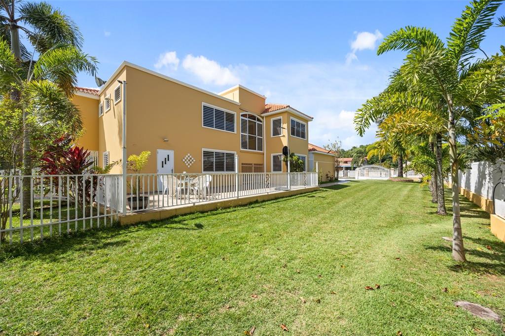 A two-story yellow house with a fenced patio and a large grassy lawn — HACIENDA LAS PALMA TIERRAS NUEVAS, MANATI, PR