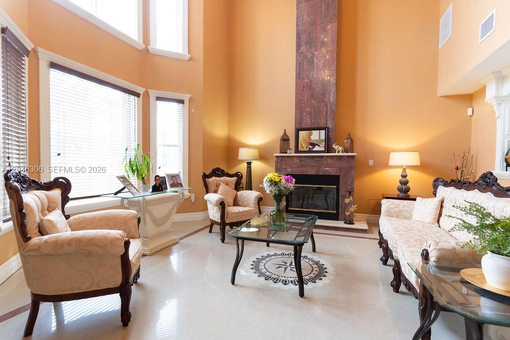 A formal living room features a tall fireplace, light-colored tile floors, and traditional upholstered furniture — 13370 SW 34th St, Miami FL 33175, MIAMI, FL