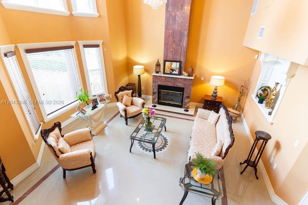 A high-ceilinged living room features a marble fireplace, beige furniture, and light tile flooring — 13370 SW 34th St, Miami FL 33175, MIAMI, FL