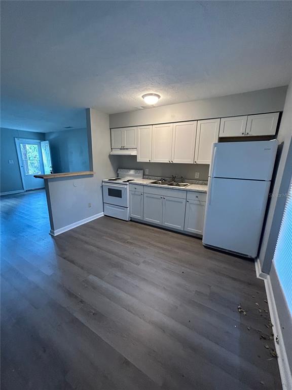 A kitchen with white cabinets, white appliances, and gray wood-look flooring — 2212 SE 36TH TERRACE UNIT A, GAINESVILLE, FL