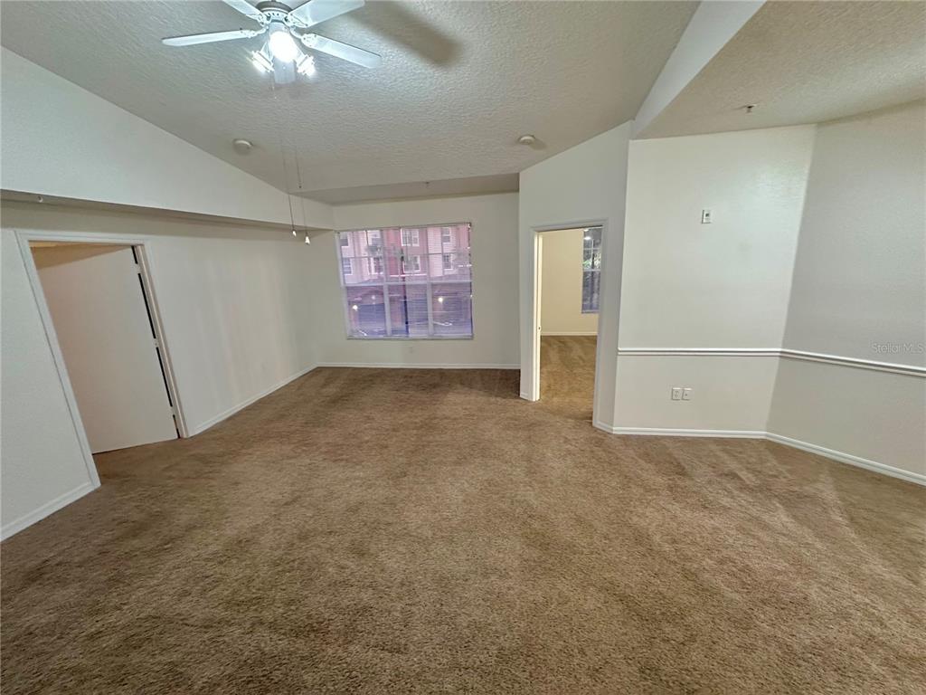 An empty room with beige carpet, white walls, a ceiling fan, and two doorways — 5554 METROWEST BOULEVARD UNIT 4-201, ORLANDO, FL