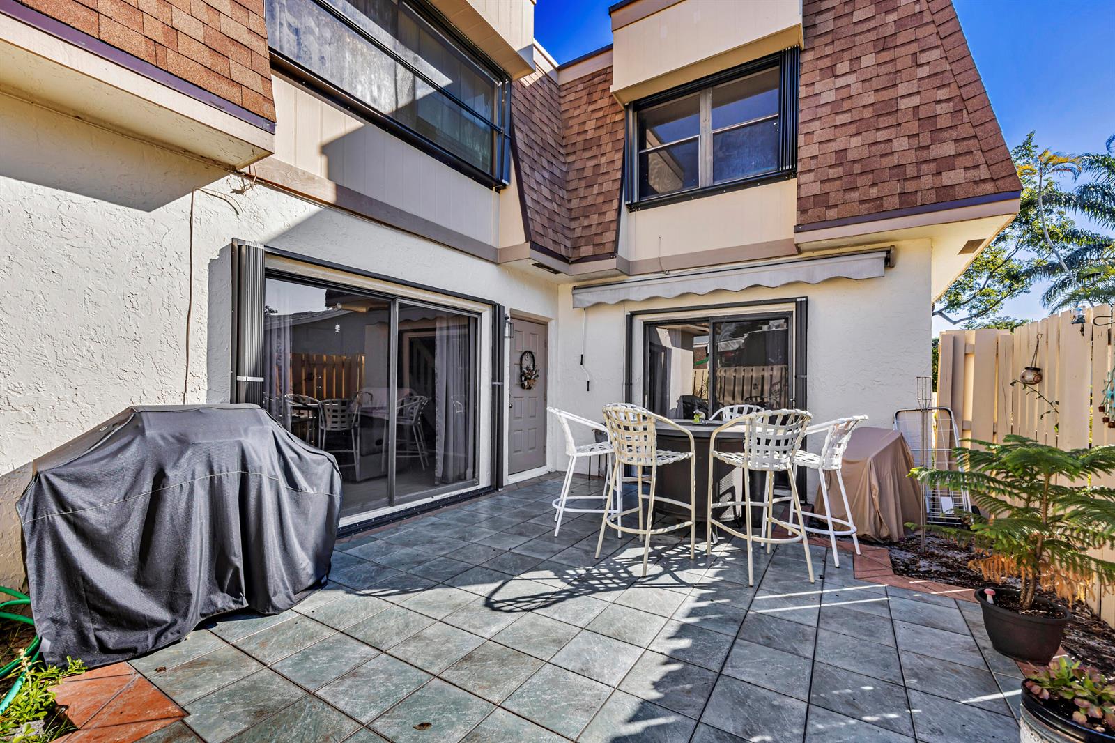 A tiled patio features a covered grill, a dining set, and sliding glass doors — 825 NW 30th Avenue # A, Delray Beach FL 33445, DELRAY BEACH, FL