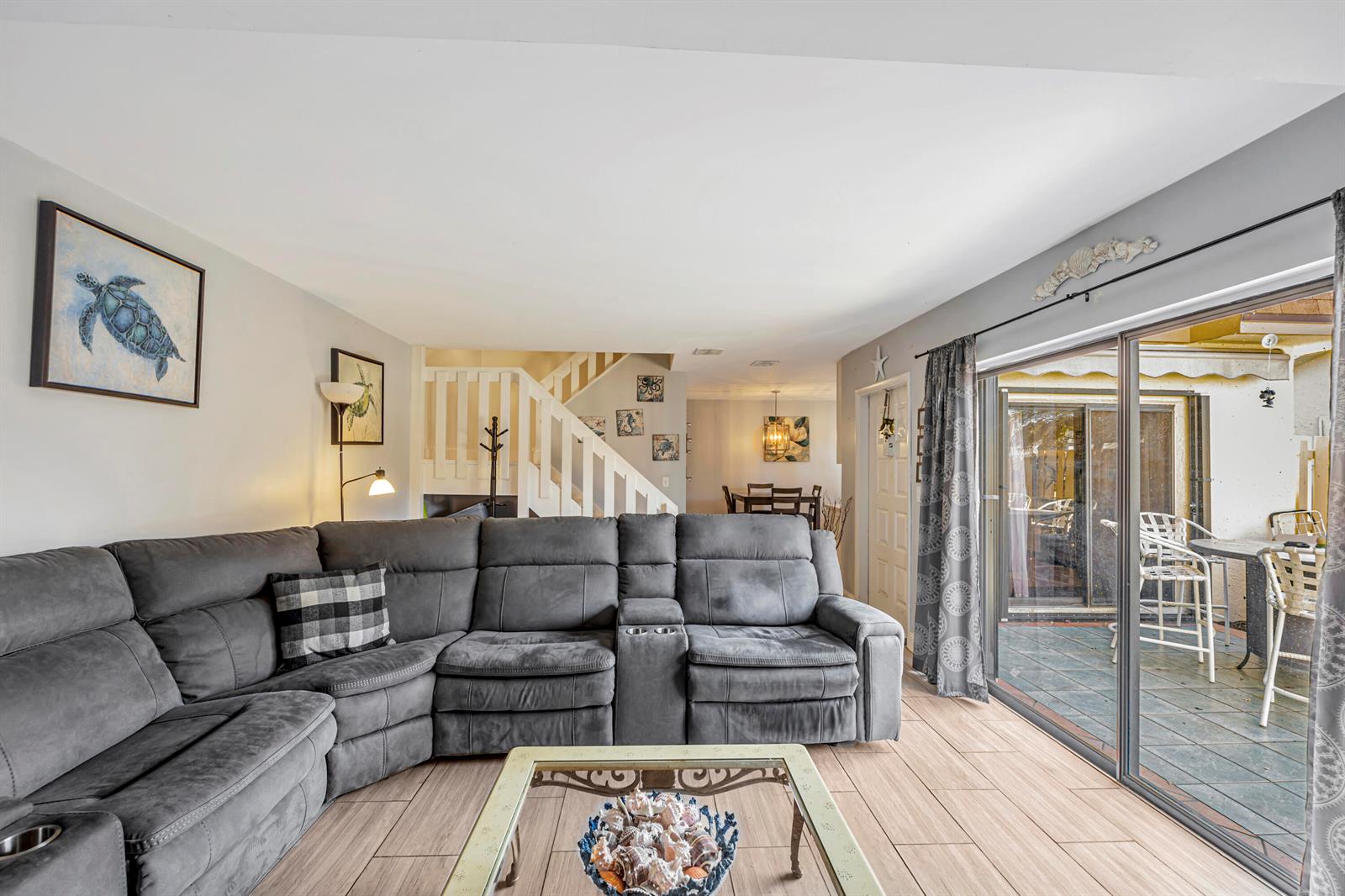 A living room features a grey sectional sofa, tile flooring, and a sliding glass door — 825 NW 30th Avenue # A, Delray Beach FL 33445, DELRAY BEACH, FL