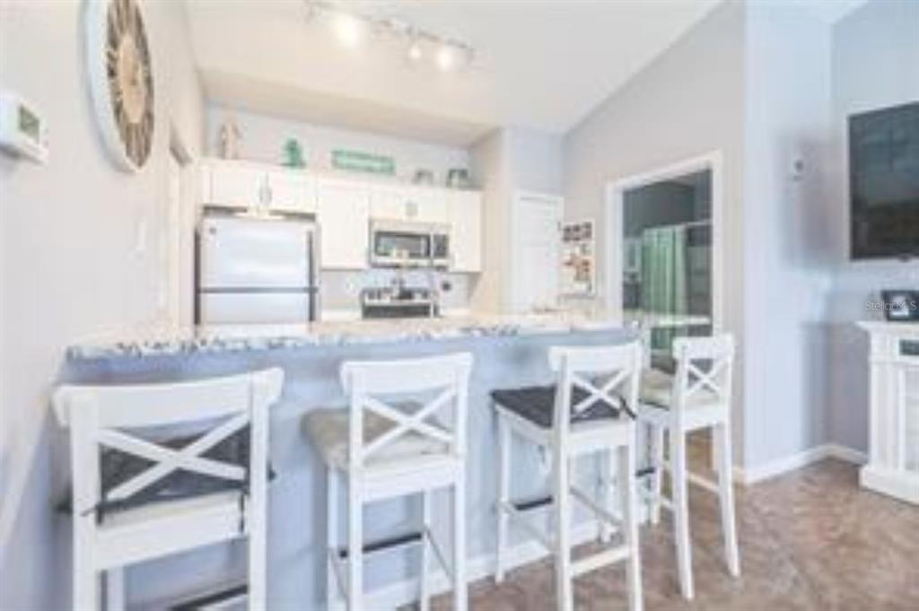 A kitchen with white cabinets and a breakfast bar featuring three wooden stools — 10764 70TH AVENUE UNIT 3305, SEMINOLE, FL