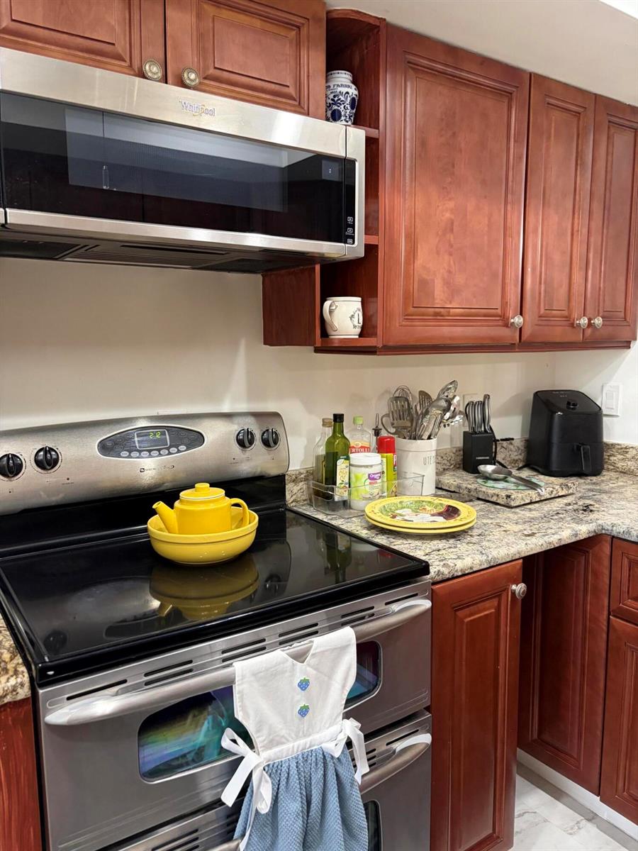 A kitchen features cherry wood cabinets, stainless steel appliances, and granite countertops — 6285 Tall Cypress Circle, FL 33463, FL