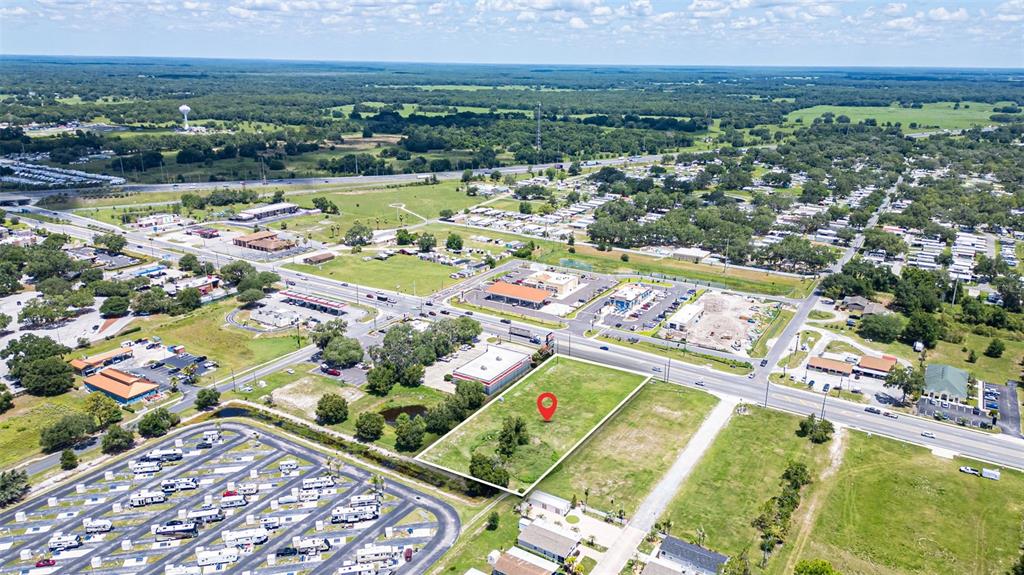 An aerial view shows a vacant rectangular lot marked with a red pin near roads — 1919 W C 48, BUSHNELL, FL