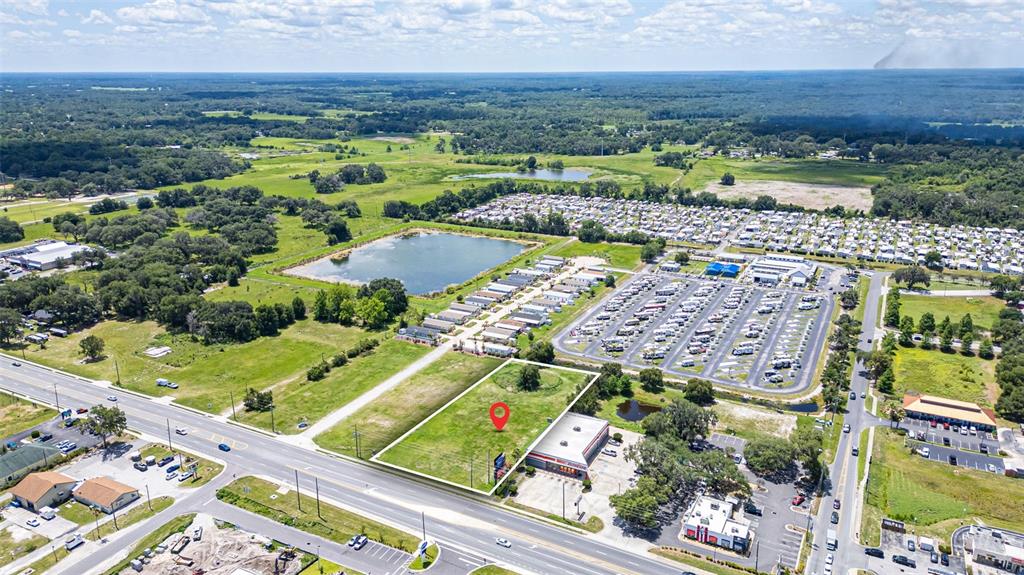 An aerial view shows a vacant rectangular lot marked with a red pin near roads — 1919 W C 48, BUSHNELL, FL