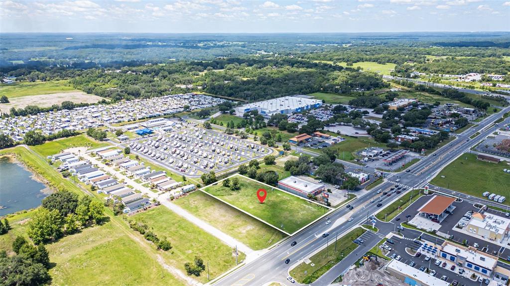 An aerial view shows a vacant rectangular lot highlighted by a red location pin — 1919 W C 48, BUSHNELL, FL