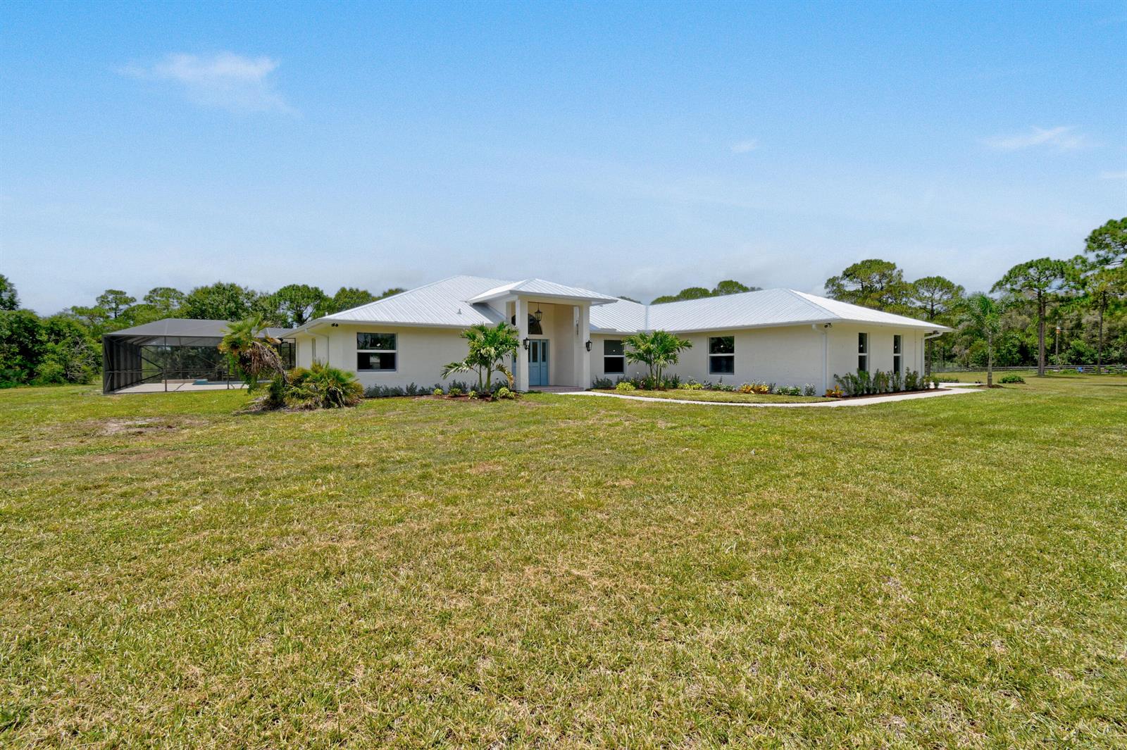 A single-story house with a light-colored exterior, metal roof, and a screened-in pool area — 425 N Ffa Road, Fort Pierce FL 34945, FORT PIERCE, FL
