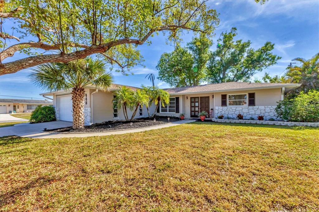 A single-story house with a beige exterior, stone accents, and a palm tree in front — 448 REDWOOD ROAD, VENICE, FL