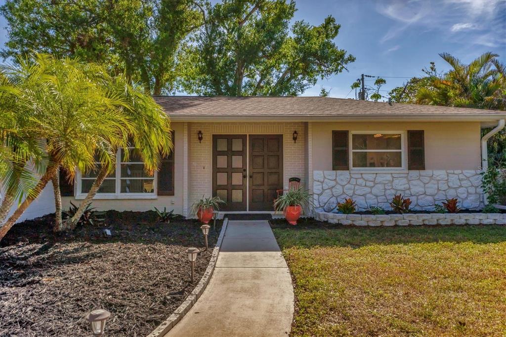 A single-story house with a brick facade, double front doors, and a stone-accented exterior wall — 448 REDWOOD ROAD, VENICE, FL