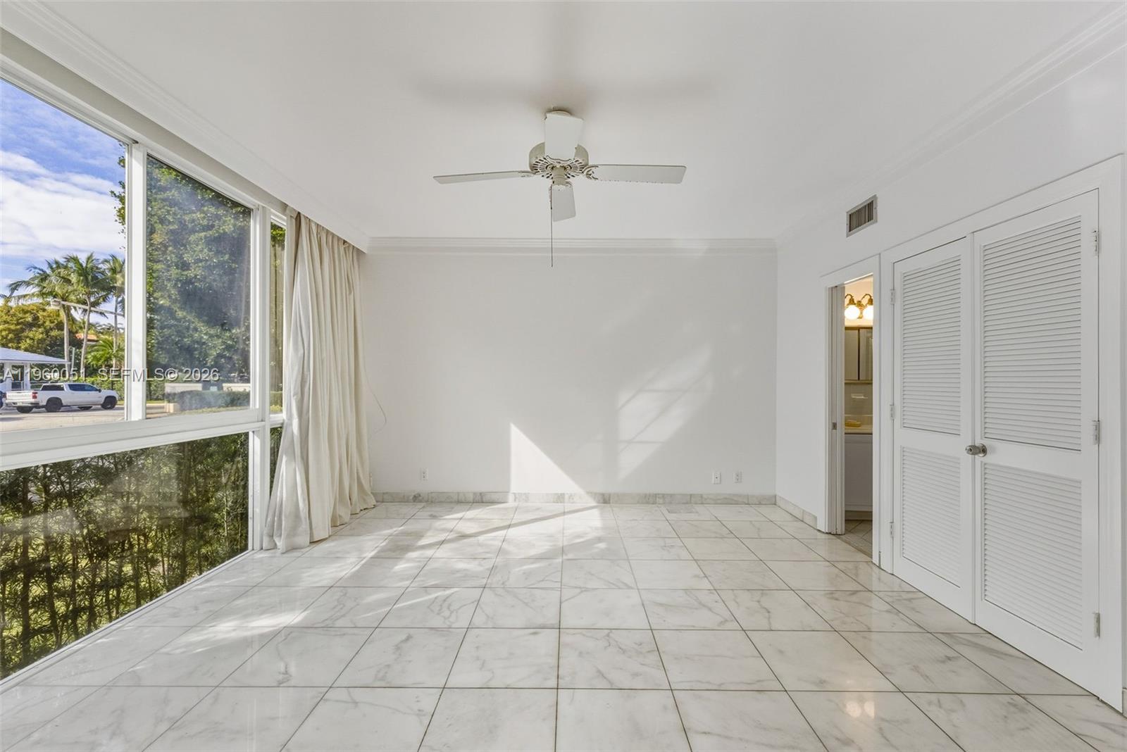A bright, empty room features white marble tile floors, a ceiling fan, and large windows — 1 Harbour Way # 108, Bal Harbour FL 33154, BAL HARBOUR, FL