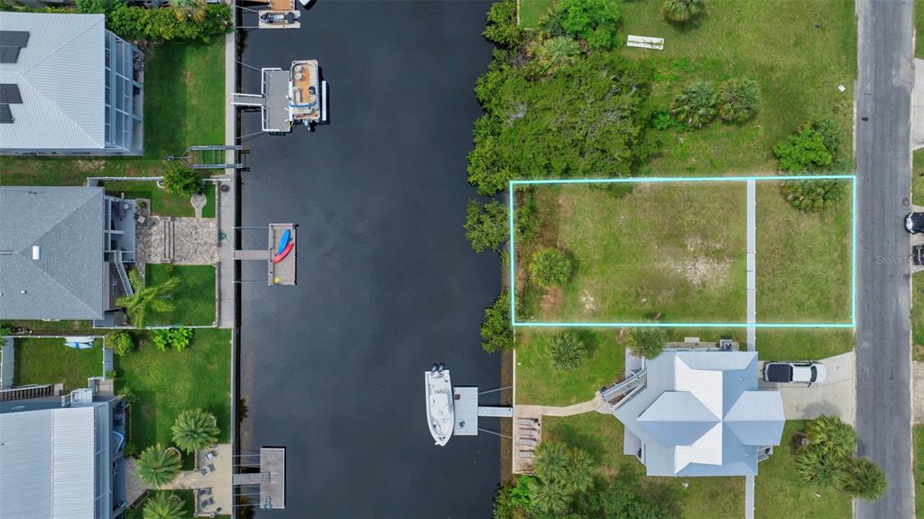 An aerial view shows a vacant, rectangular waterfront lot outlined in blue next to a canal — CENTAVO COURT, HERNANDO BEACH, FL