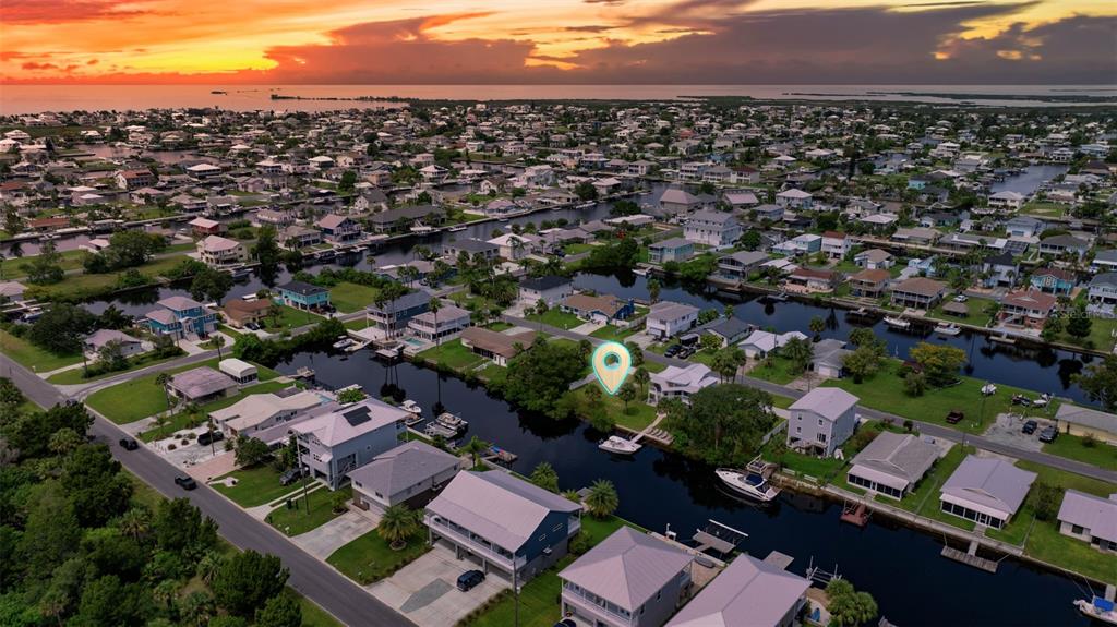 An aerial view shows a waterfront residential neighborhood at sunset with a highlighted property location — CENTAVO COURT, HERNANDO BEACH, FL