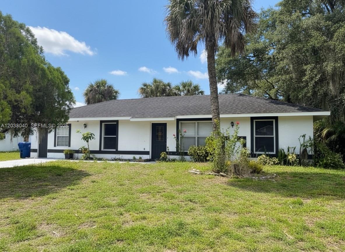 A single-story white house with a dark roof and black trim sits on a lawn — 4029 E Sunflower Cir, La Belle FL 33935, LA BELLE, FL