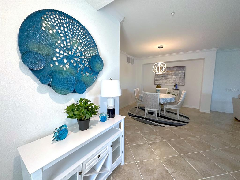 A white console table with blue decor sits in a foyer leading to a dining area — 14649 SYCAMORE COURT UNIT 2912, PUNTA GORDA, FL