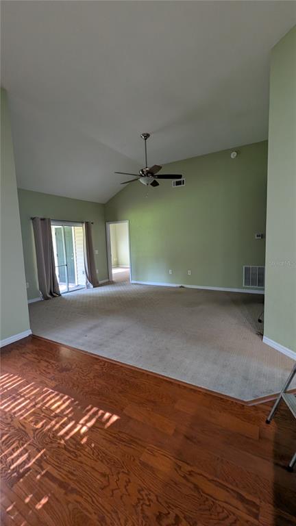 A living room features vaulted ceilings, a ceiling fan, beige carpeting, and hardwood flooring — 13200 W NEWBERRY ROAD UNIT Z144, NEWBERRY, FL