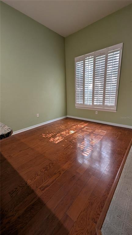 An empty room features light green walls, hardwood flooring, and a window with white shutters — 13200 W NEWBERRY ROAD UNIT Z144, NEWBERRY, FL