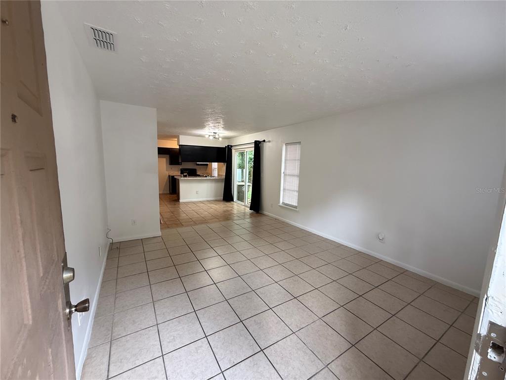 An open-concept living area with light-colored floor tiles leads to a kitchen in the back — 2710 NE 23RD AVENUE, OCALA, FL