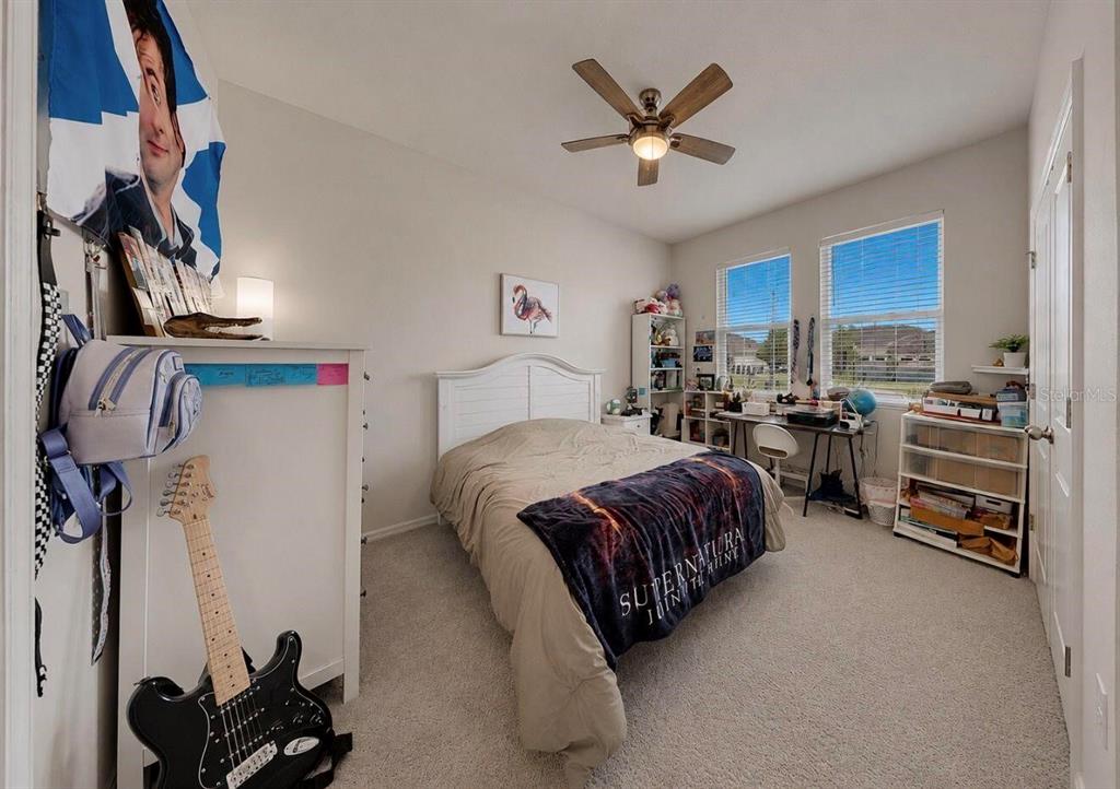 A bedroom features a bed with a Supernatural blanket, a guitar, and two windows — 11043 TAMARACK PLACE, PARRISH, FL