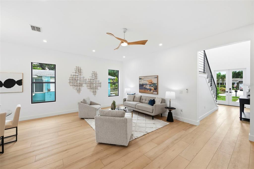 A bright living room features light wood floors, a modern ceiling fan, and neutral furniture — 6325 11TH AVENUE S, GULFPORT, FL