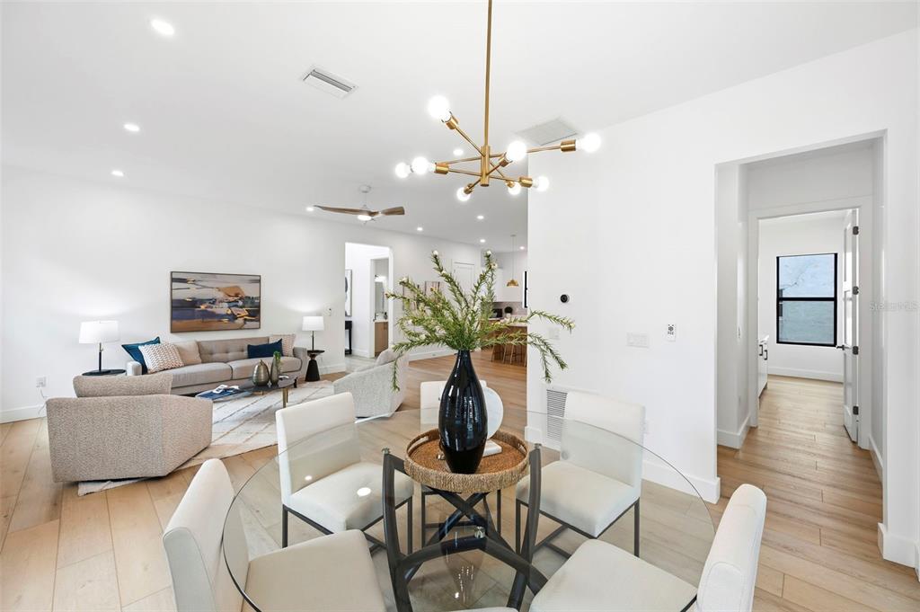 A bright, open-concept dining and living area features light wood floors and modern light fixtures — 6325 11TH AVENUE S, GULFPORT, FL