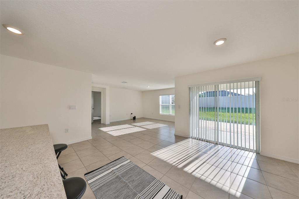 An open-concept living area features light tile flooring, recessed lighting, and sliding glass patio doors — 16782 CARLTON POND STREET, WIMAUMA, FL