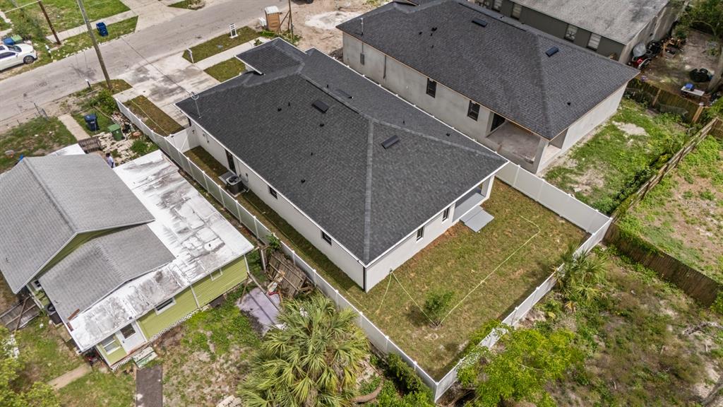 An aerial view shows a modern house with a dark roof next to a smaller home — 8210 N ELMER STREET, TAMPA, FL