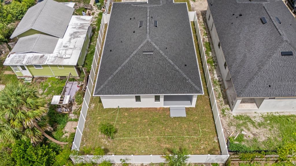 An aerial view shows the back of a house with a fenced yard and roof — 8210 N ELMER STREET, TAMPA, FL